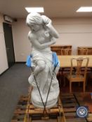 A contemporary carved solid white marble statue of a semi-nude female seated on a rock,