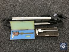 A camera tripod together with two cased precision instruments