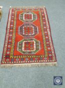 A Caucasian design rug on red ground,