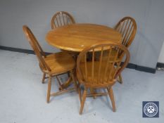 A circular pine pedestal kitchen table together with four chairs