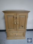 A stripped pine double door cabinet