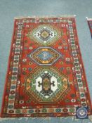 A Caucasian design rug on red ground,