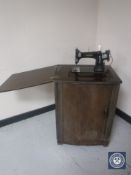 A mid 20th century Jones treadle sewing machine in cupboard