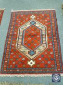 A Caucasian design rug on red ground,