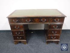 A mahogany twin pedestal writing desk fitted nine drawers with tooled green leather inset panel