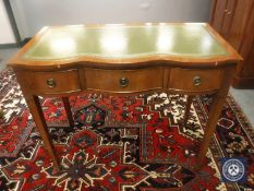 A Georgian style serpentine front desk fitted three drawers, with tooled green leather top,