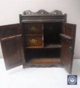 A Victorian oak double door smoker's cabinet with carved panel doors