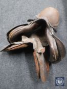 Two brown leather saddles