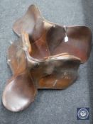 Two brown leather saddles