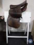 Two leather saddles and wooden stand