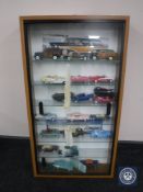 A sliding door display case containing a collection of die cast vehicles