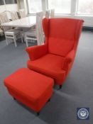 A contemporary button back wing armchair with stool in red fabric