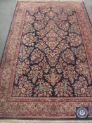 A fringed woollen floral rug on blue ground