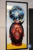 A colour photograph depicting the footballer Pele with a silver-coloured football balanced in his