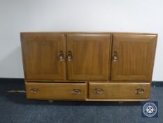 An Ercol elm triple door sideboard