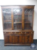 A mahogany Regency style triple door bookcase fitted cupboards and drawers beneath with lion mask