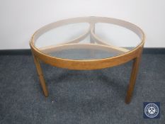 A circular teak glass topped coffee table
