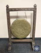 An early 20th century brass dinner gong on a carved oak frame