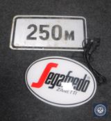 An illuminated Segafredo sign and a 250m road sign