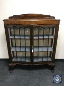 An antique mahogany serpentine fronted display cabinet on claw and ball feet