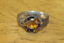 An antique silver bangle set with coloured stones