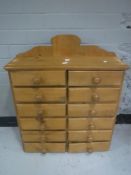 A pine wall cabinet fitted twelve drawers