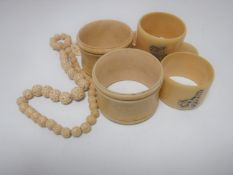 Five antique ivory napkin rings together with a beaded necklace