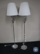 A pair of contemporary chrome floor lamps with white shades