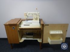 A 20th century teak sewing cabinet containing a Singer Magic machine