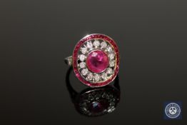 An 18ct white gold ruby and diamond cluster ring, a central oval-cut, deep red ruby weighing 1.