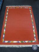 A set of three fringed woolen rugs on red ground