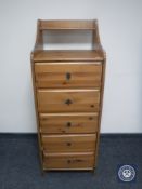 A narrow pine five drawer chest
