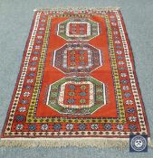 A Caucasian design rug on red ground,