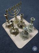 A tray of five ornate brass candlesticks and a brass menorah