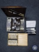 An oak canteen of cutlery and two boxed cutlery sets