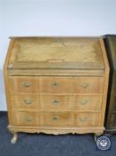 A blond oak bureau fitted three drawers