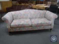A two seater scroll arm settee upholstered in a multi coloured fabric