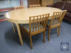 An oval pine effect dining table with two leaves together with a set of four chairs