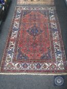 An Iranian Hamadan rug, an indigo pole medallion upon a salmon field tribal motifs,