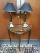 A walnut pie crust edge D-shaped hall table together with a pair of table lamps
