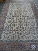 A fringed floral carpet on cream ground