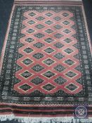 An Afghan design rug on salmon ground,