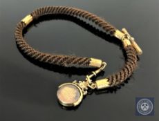 A Victorian braided hair and yellow metal ornament with Lord's Prayer swivel fob,