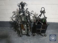 Two wrought iron hanging light fittings with leaded glass shades
