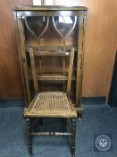 An oak display cabinet and a rush seated bedroom chair