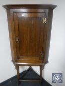 A George III and later oak corner cabinet on stand
