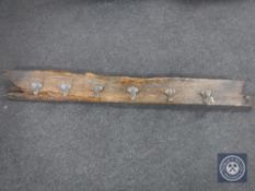 A set of six cast iron coat hooks mounted on a pine board