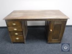 An Edwardian oak desk fitted with a cupboard and four drawers