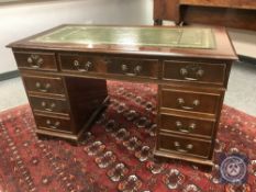 A reproduction twin pedestal desk with green tooled leather top,