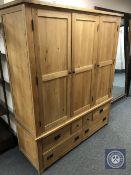 A contemporary light oak triple door wardrobe fitted with six drawers,